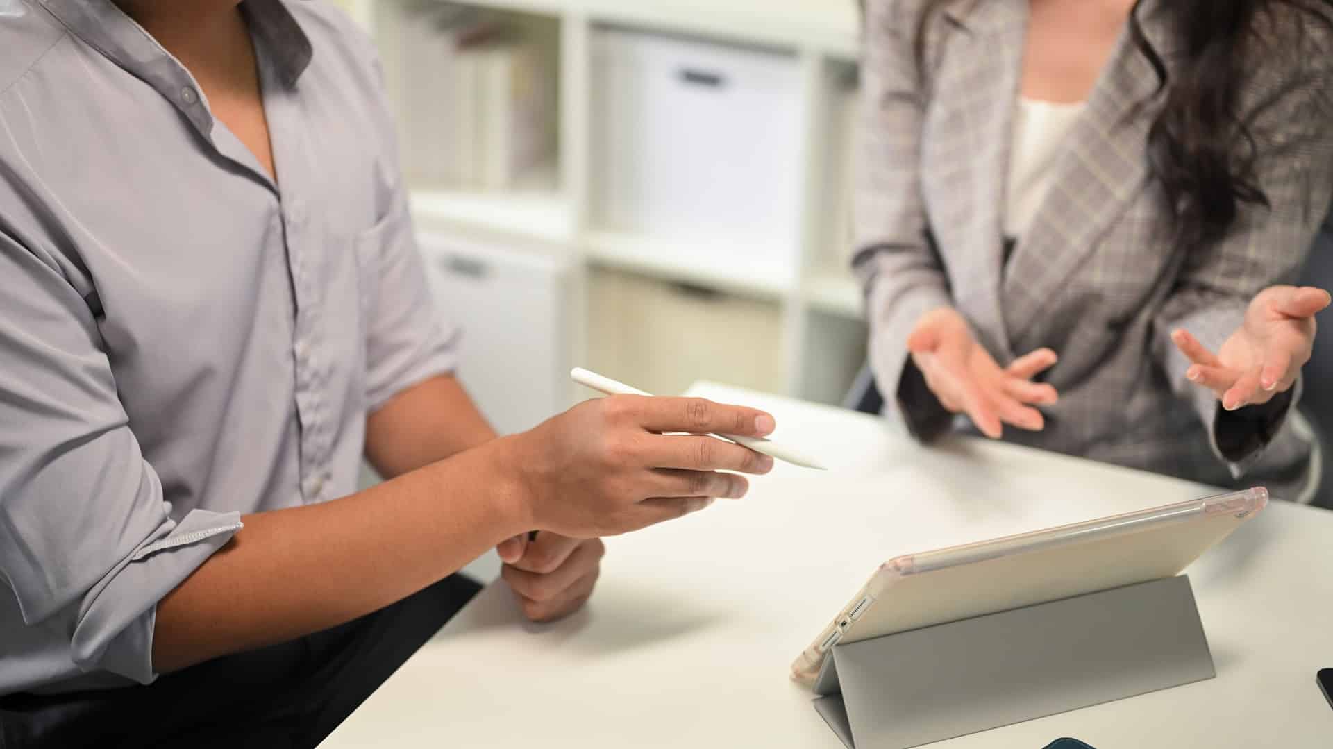 Close up of office workers reviewing data and sharing strategies on digital tablet